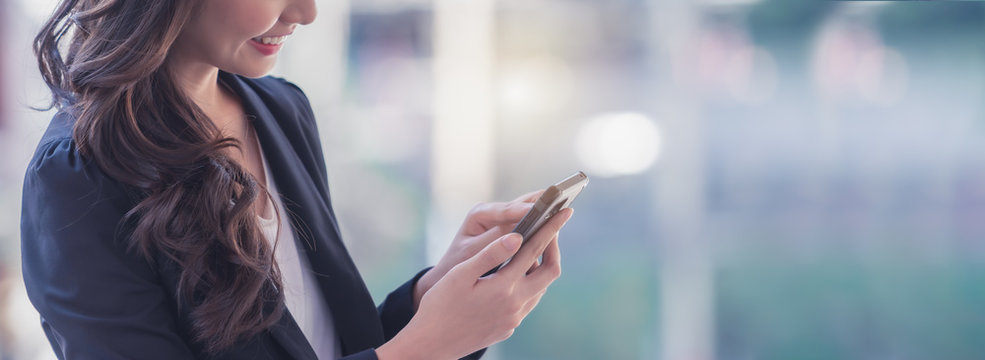A professional woman smiling and using her smartphone to contact