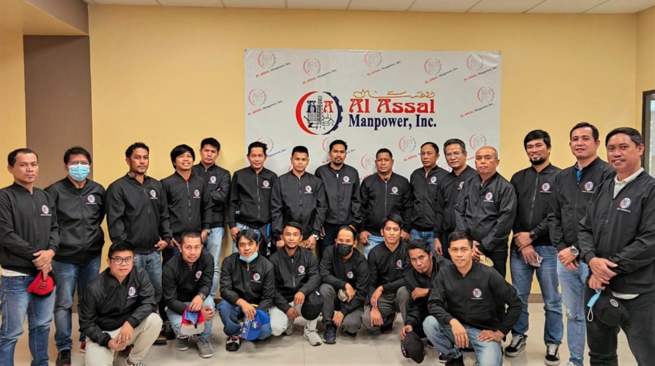 A group of deployed workers photo of the Al Assal Manpower, Inc. in their company jackets.