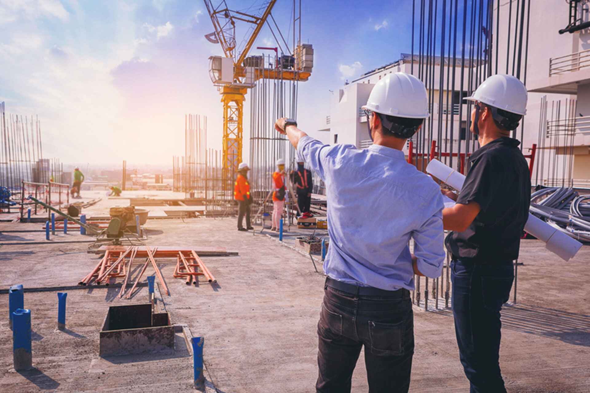 Two engineers in hard hats reviewing blueprints at a construction site, symbolizing our expertise in industrial and engineering placements