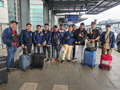 A group of Filipino workers with luggage at an airport, ready for overseas deployment.